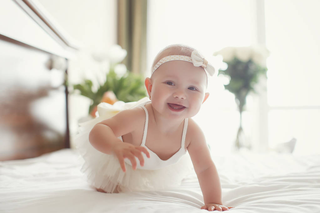 Baby girl crawling on bed and laughing